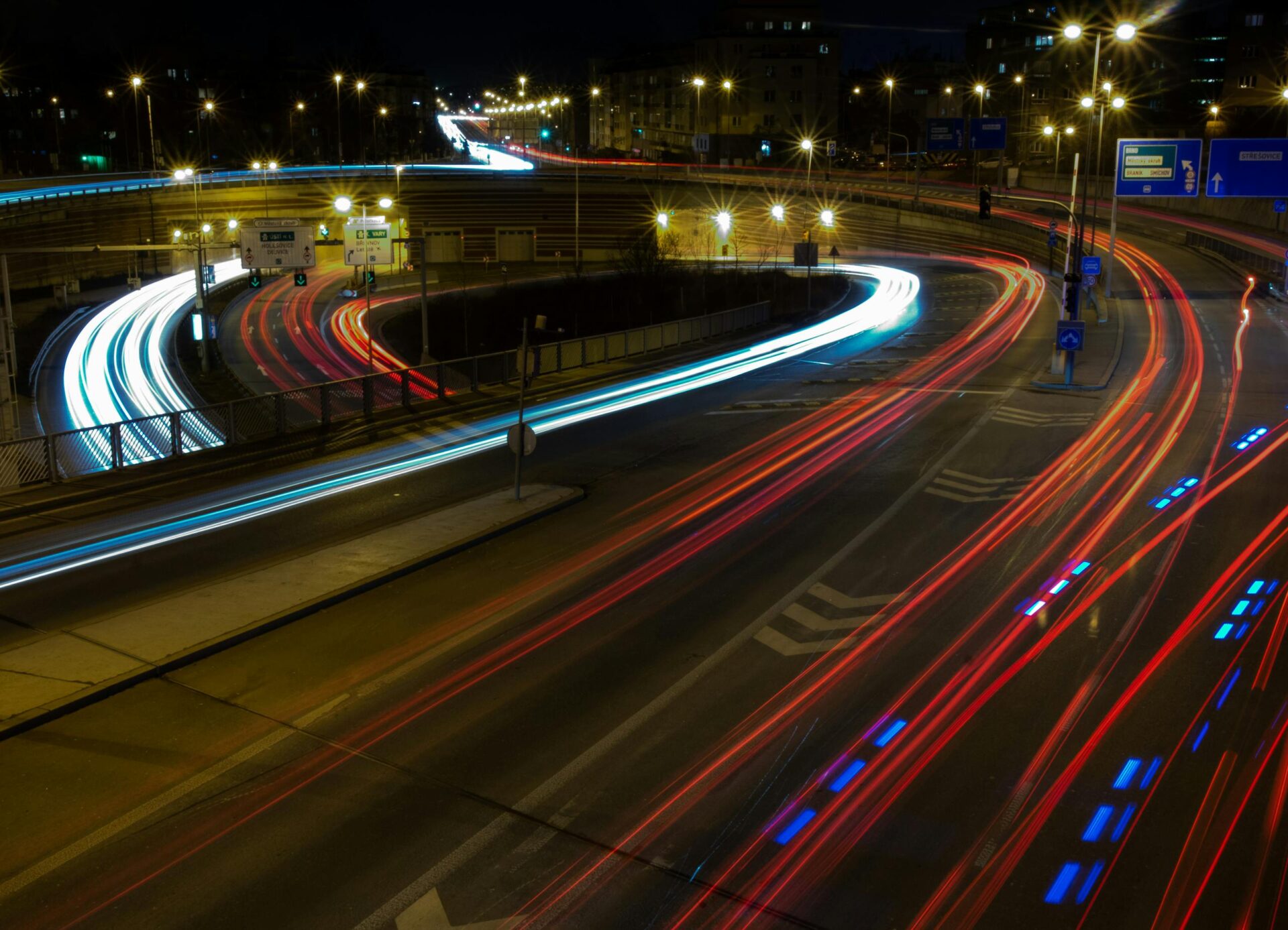Vibrant light trails create a dynamic urban scene on a bustling highway at night.
